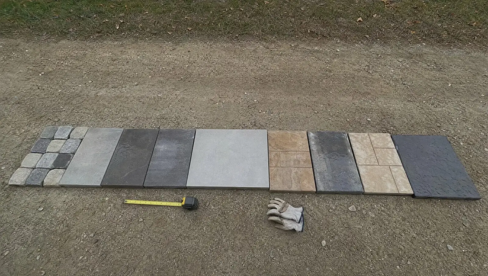 Concrete paver samples laid out side by side on a driveway to compare colours and textures.