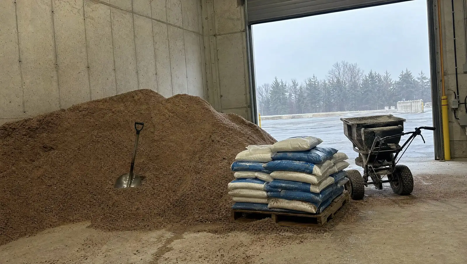 Bulk rock salt and bagged calcium chloride stocked with a broadcast spreader for winter.