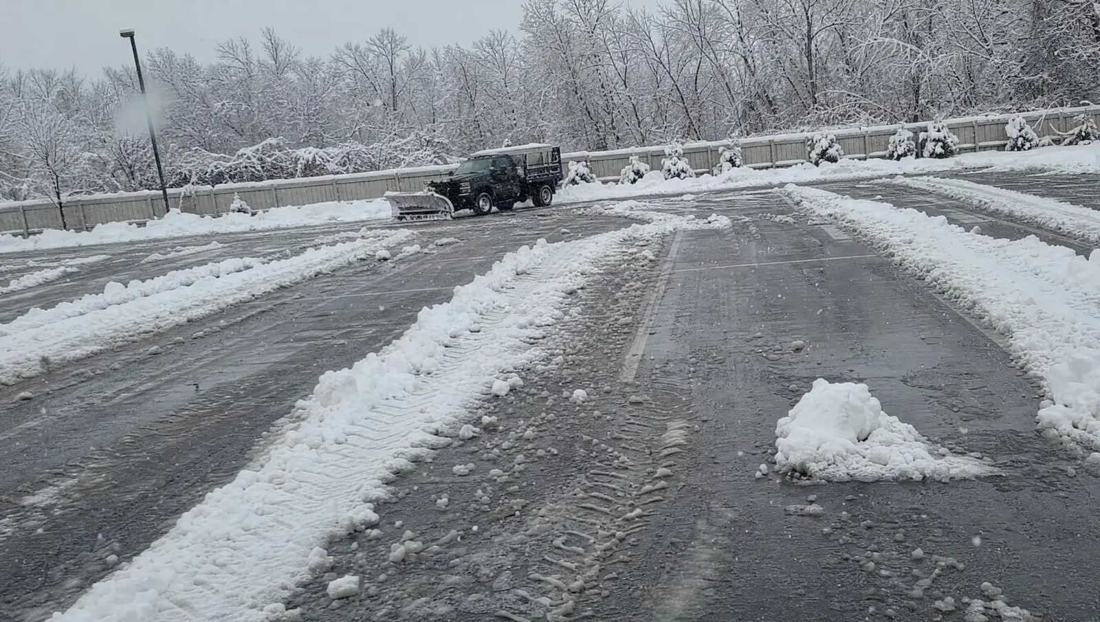 Plow windrows and bare asphalt across a Connecticut commercial lot during a snow event.