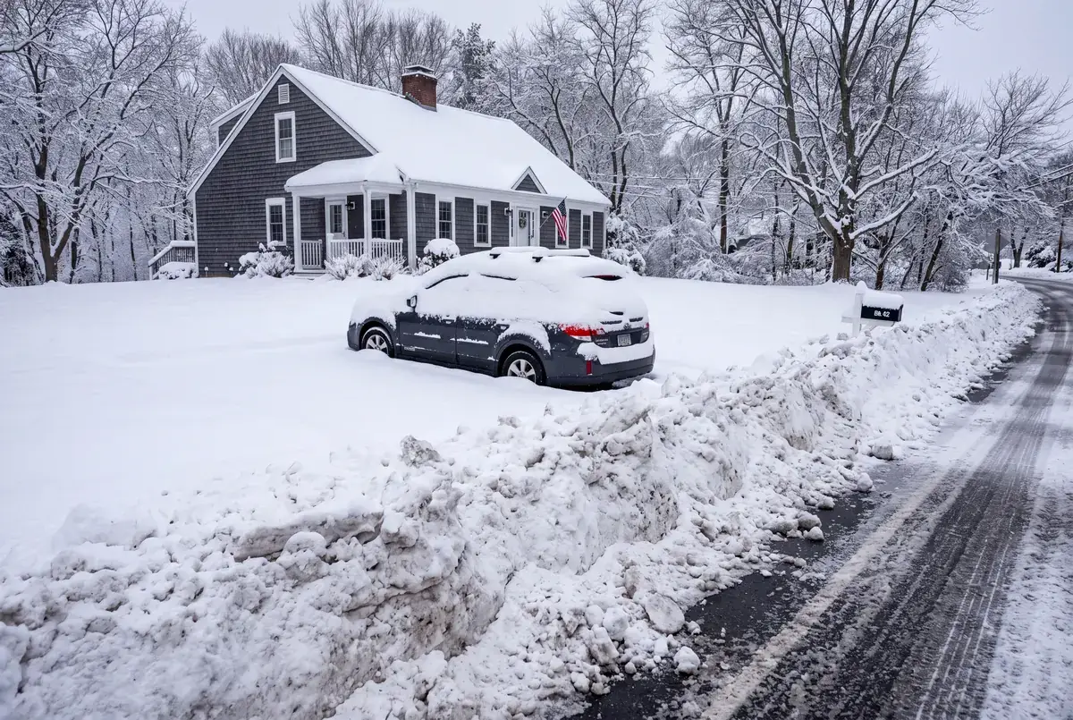Car buried in a snowed-in driveway with a plow pile at the street, the morning homeowners look for snow removal in Mystic CT