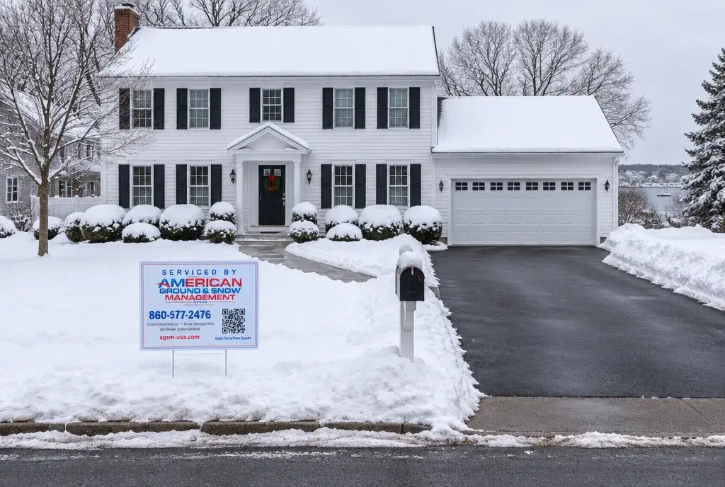Residential snow plowing in Mystic CT, a driveway plowed to bare pavement with an American Ground & Snow Management yard sign