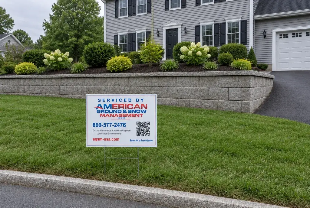 Retaining wall contractor work in Stonington CT, a finished block retaining wall with an American Ground & Snow Management yard sign