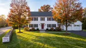 Connecticut colonial after a professional fall cleanup with a clean green lawn, clear beds, and AGSM yard sign