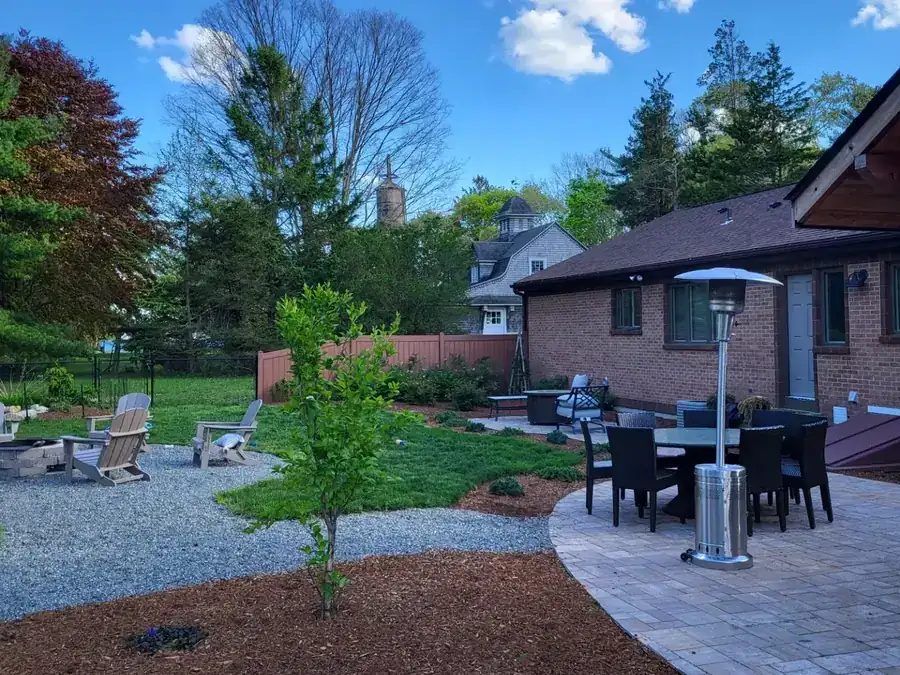 Finished backyard with a paver patio, mulched beds and a young tree