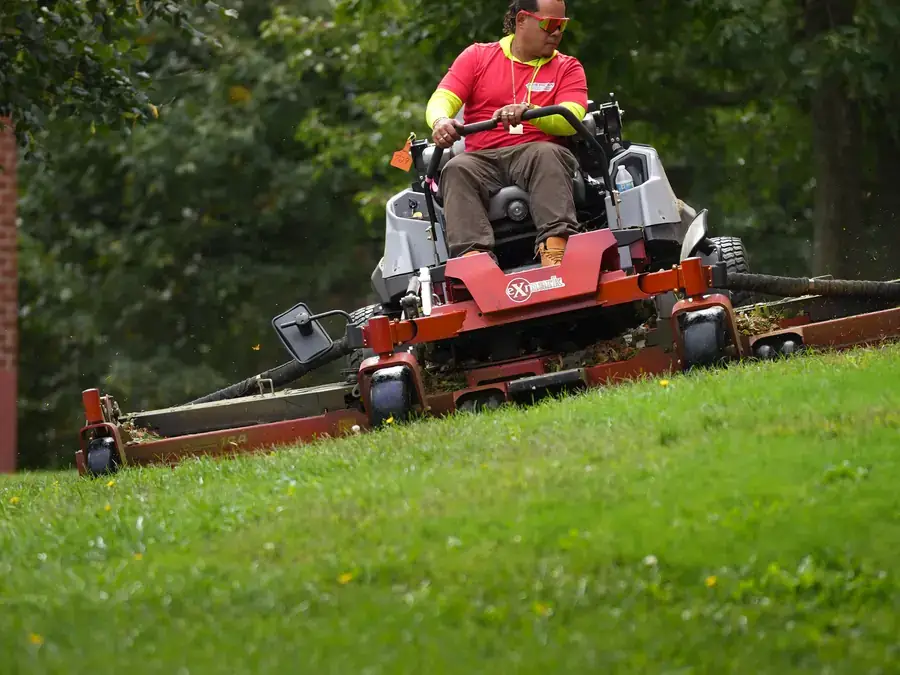 AGSM crew member mowing a steep slope on a commercial ride-on mower