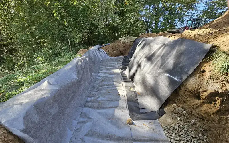 Drainage trench lined with filter fabric and stone, dug by AGSM
