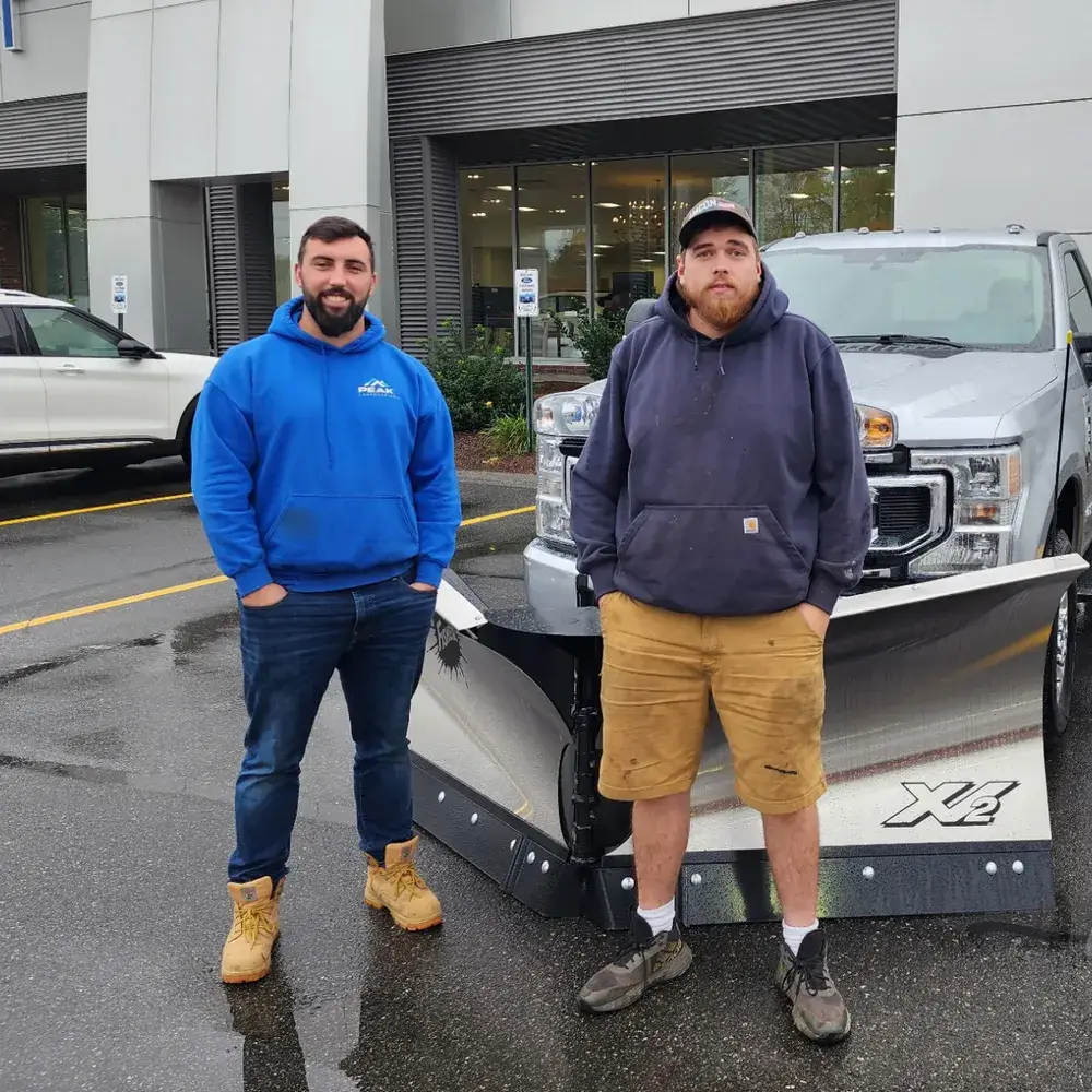 Jordan and CJ, owners of American Ground and Snow Management, with an AGSM plow truck