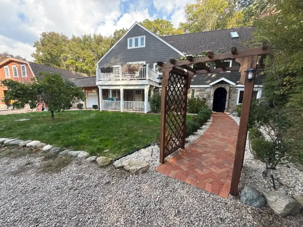 Arbor, brick path and clean gravel beds on a Stonington, CT property on monthly bush and bed care